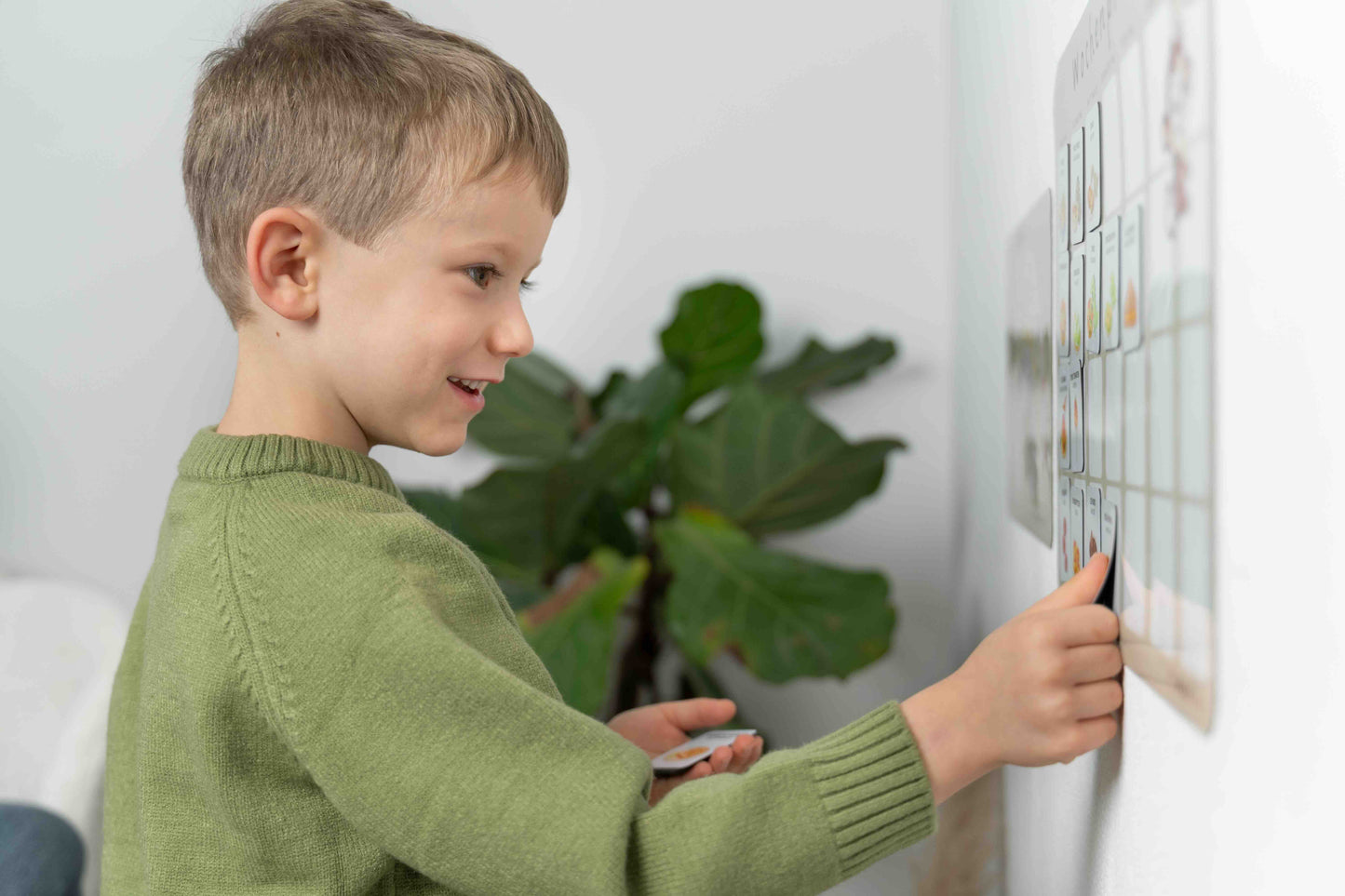 Kind befestigt Mealomat Rezepttafeln am Wochenplaner – interaktives Lernmittel für Ernährungsbildung.