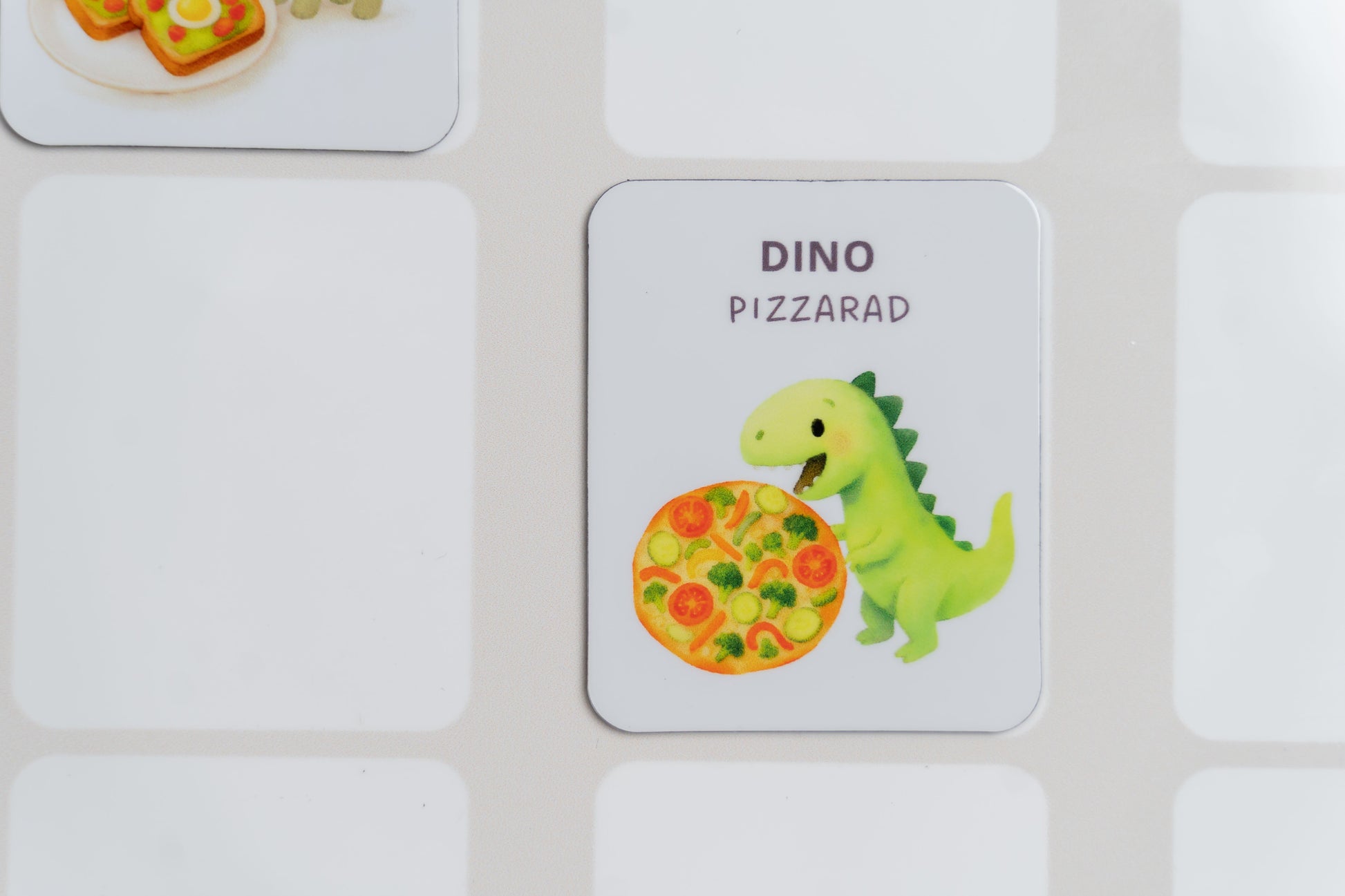 Mealomat Dino-Rezeptmagnet Pizza am Wochenplaner – für selbstständige Essensplanung von Kindern.