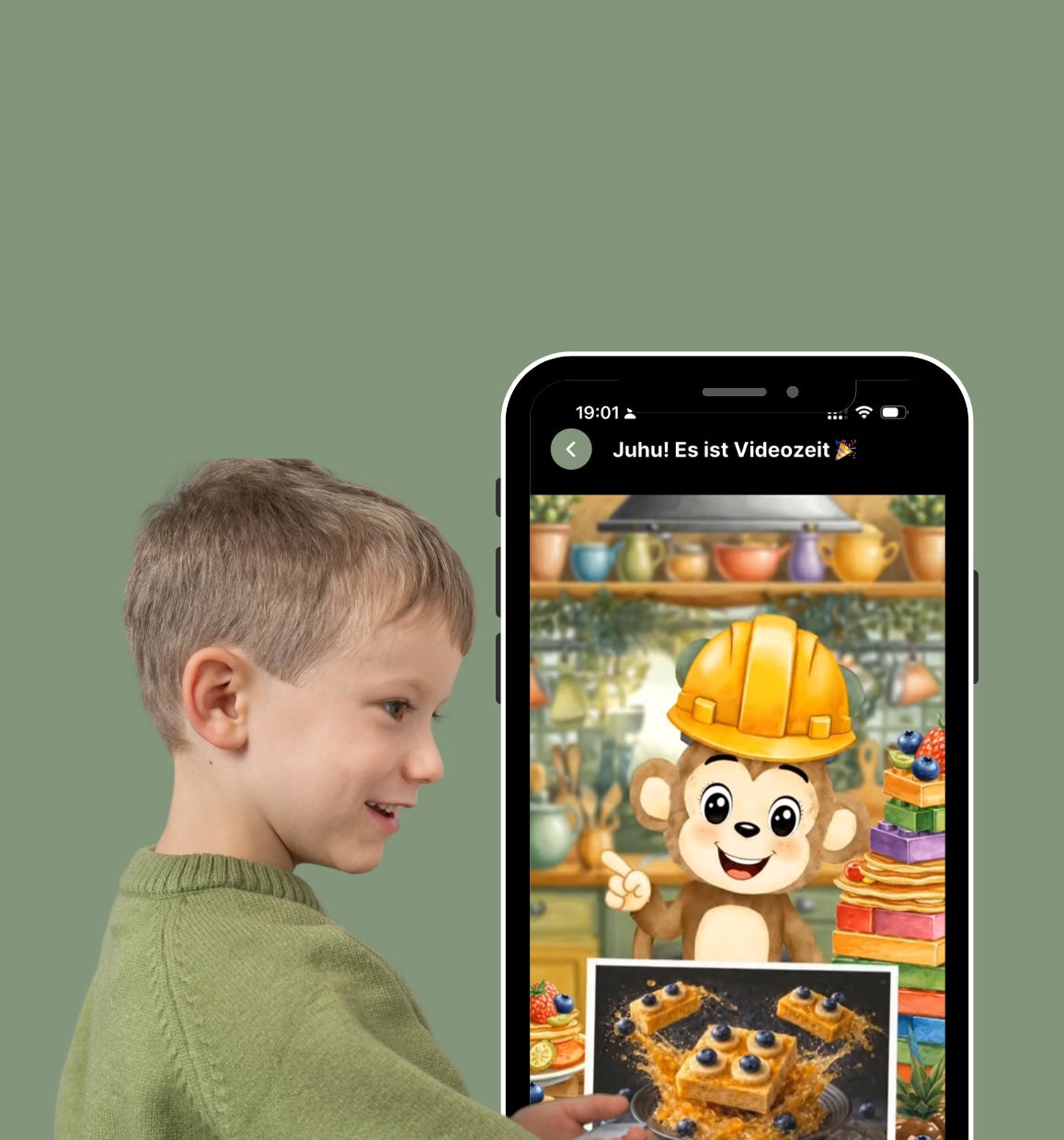 Ein fröhlicher junger Junge in einem grünen Pullover, der gespannt auf ein Smartphone schaut. Auf dem Smartphone-Display läuft ein interaktives Rezeptvideo der Mealomat-App. Ein niedliches Affen-Maskottchen im Bauarbeiter-Outfit erklärt spielerisch ein Rezept für einen gesunden Beeren-Kuchen, das auch als Foto auf dem Bildschirm zu sehen ist.